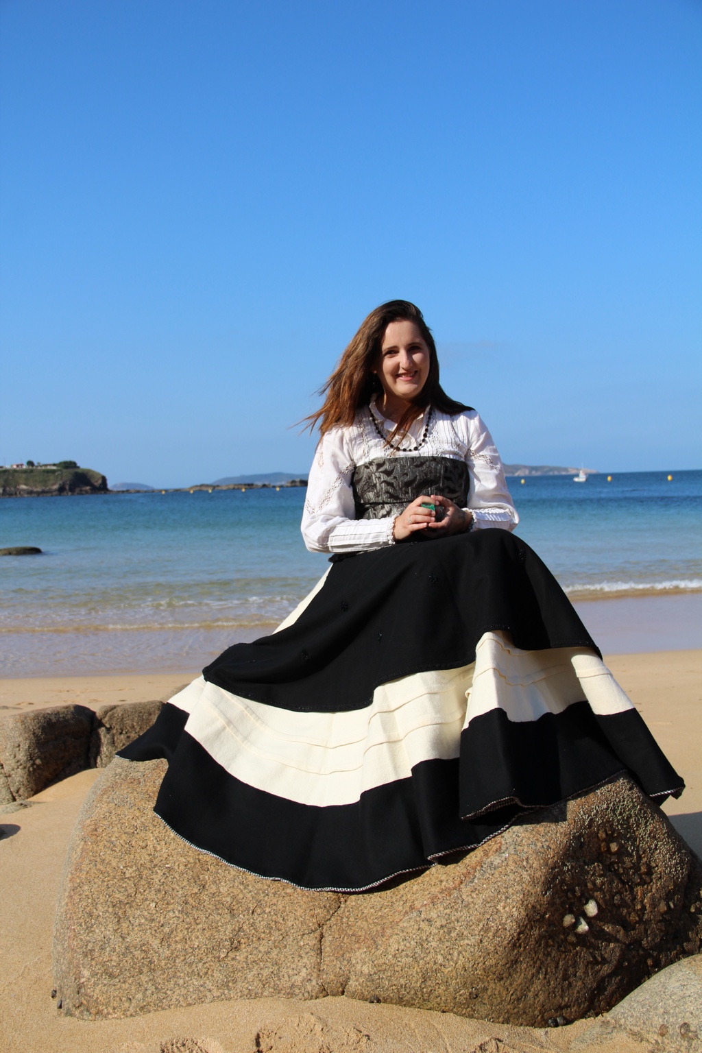 Ariadna sentada junto al mar con vestimenta gallega
